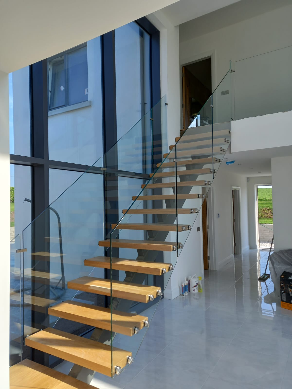 Floating Wooden Staircase With Glass Railings In A Bright Modern Interior.