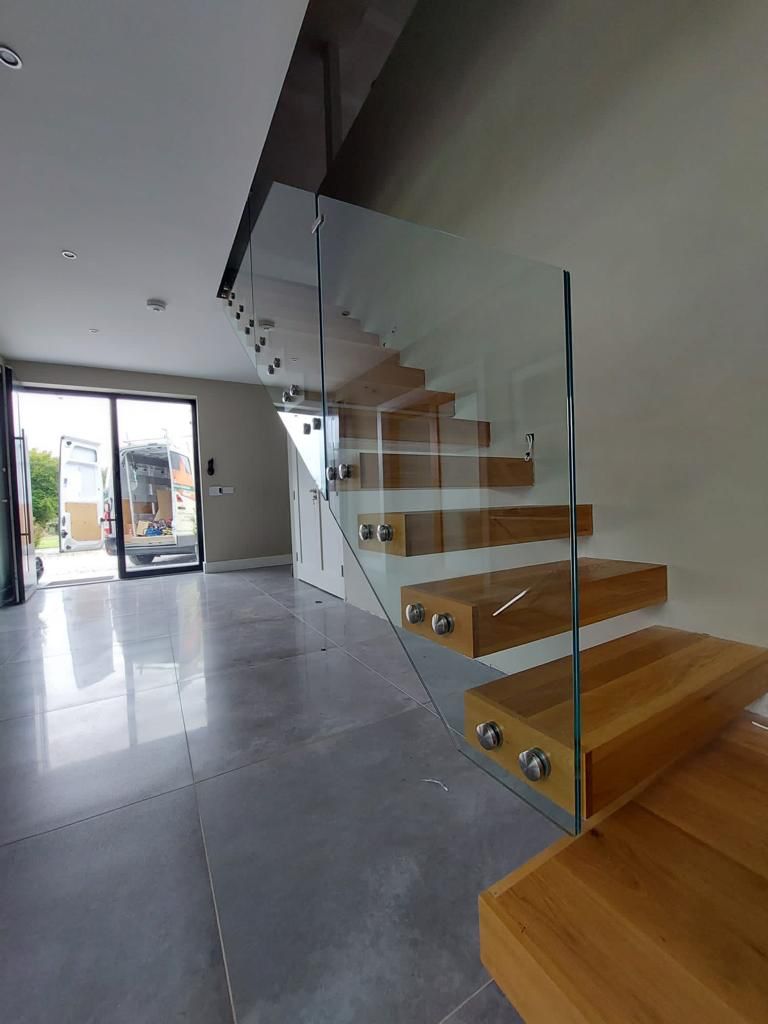 Glass Bolted Onto Cantileverd Stair Threads Modern Interior With Floating Wooden Stairs And Glass Railing Leading To The Upper Floor.