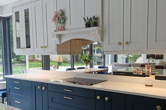 Antique Splashback Kitchen With White Upper Cabinets, Dark Blue Lower Cabinets, And Antique Mirror Splashback.