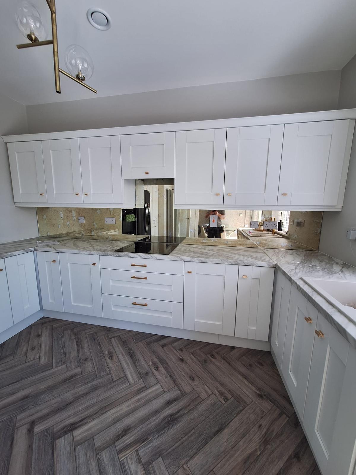 Gold Antique Mirror Splashback Modern White Kitchen With Handleless Cabinets, Herringbone Floor, And Mirrored Backsplash