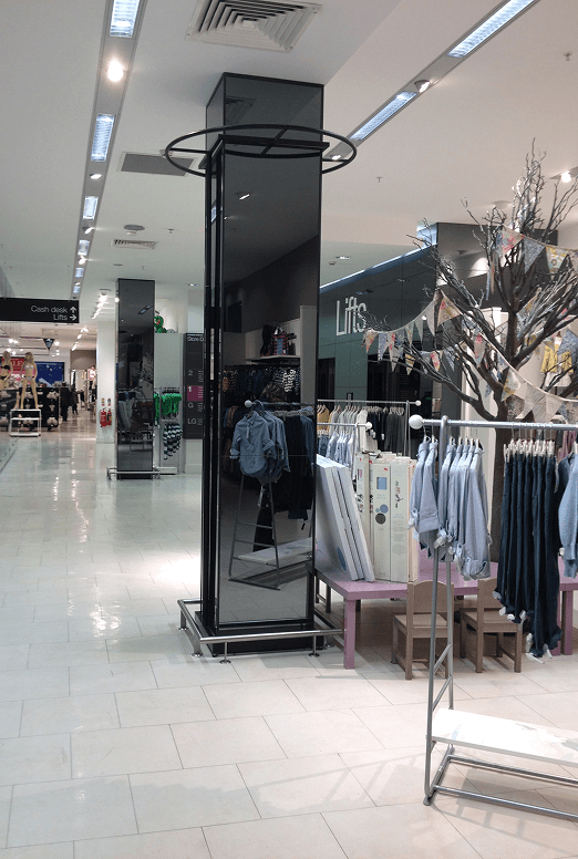 Retail Bronze Mirror Pillar Retail Store Interior With Bronze Mirror Pillar And Clothing Racks.