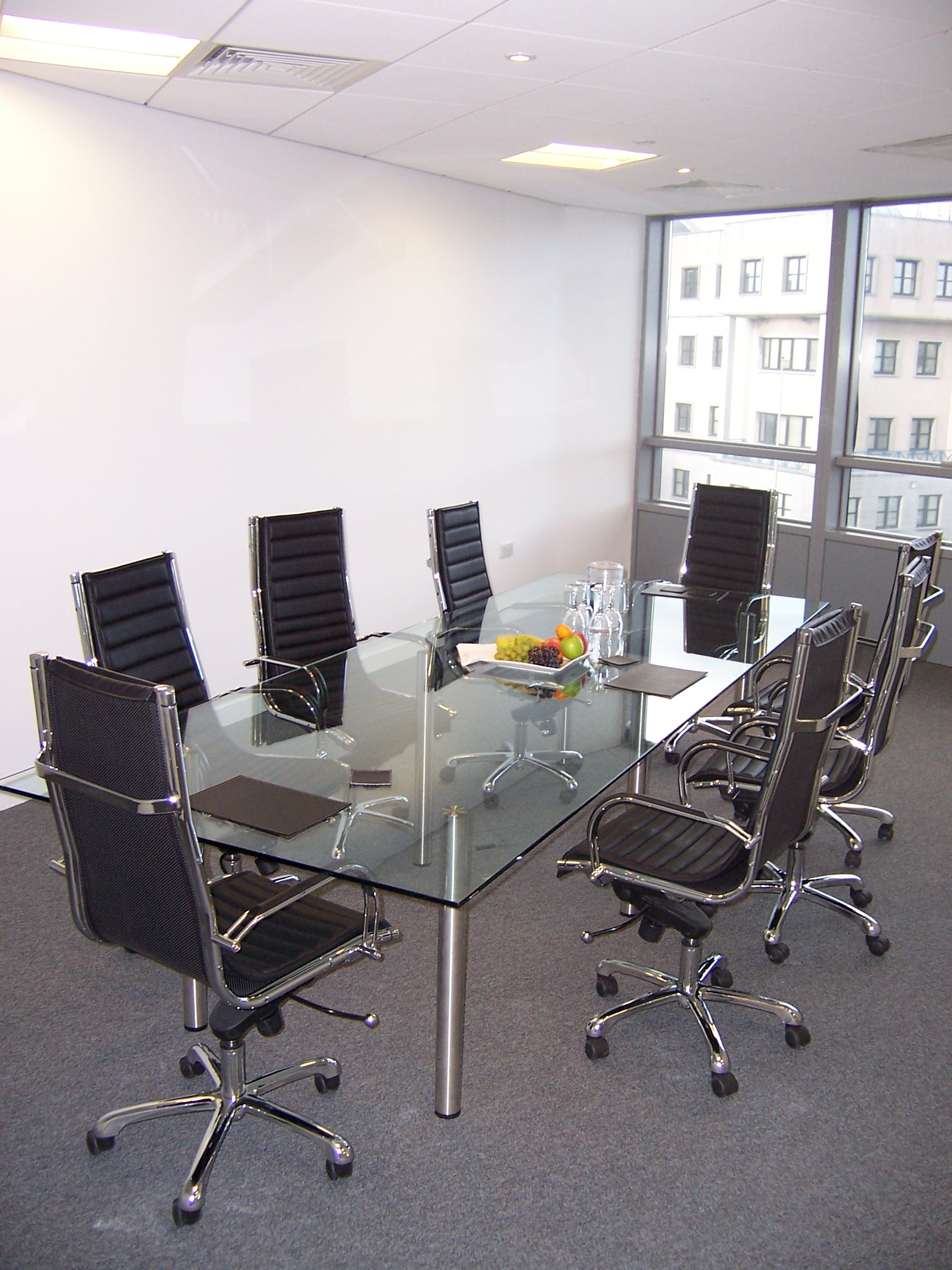 Large Glass Table Top In Boardroom Modern Conference Room With Glass Table, Black Chairs, And Natural Light