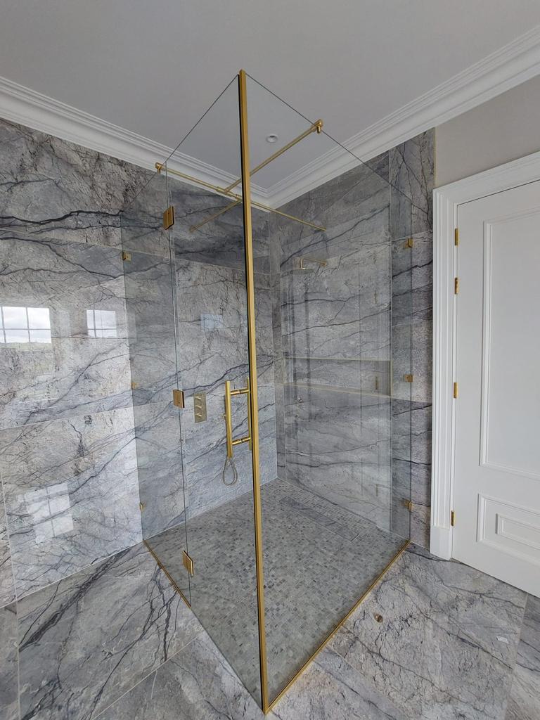 Shower Enclosure Brass Luxurious Shower Enclosure With Brass Fittings And Clear Glass, Set Against A Marble Wall.